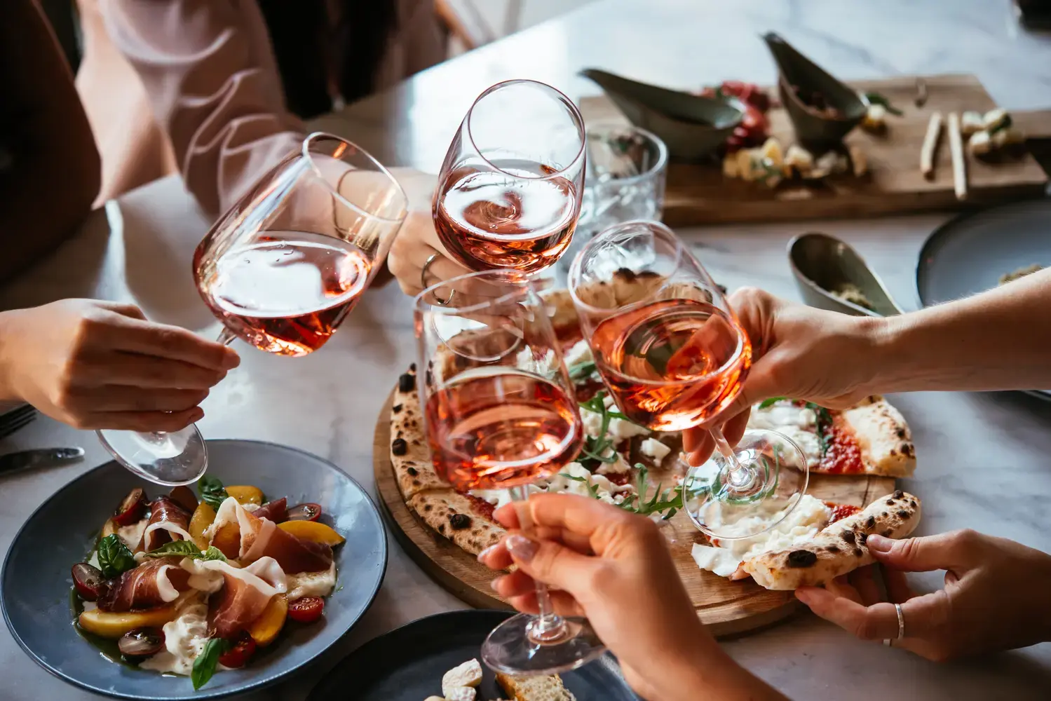 A group of people are sitting at a table with wine glasses and plates of food.